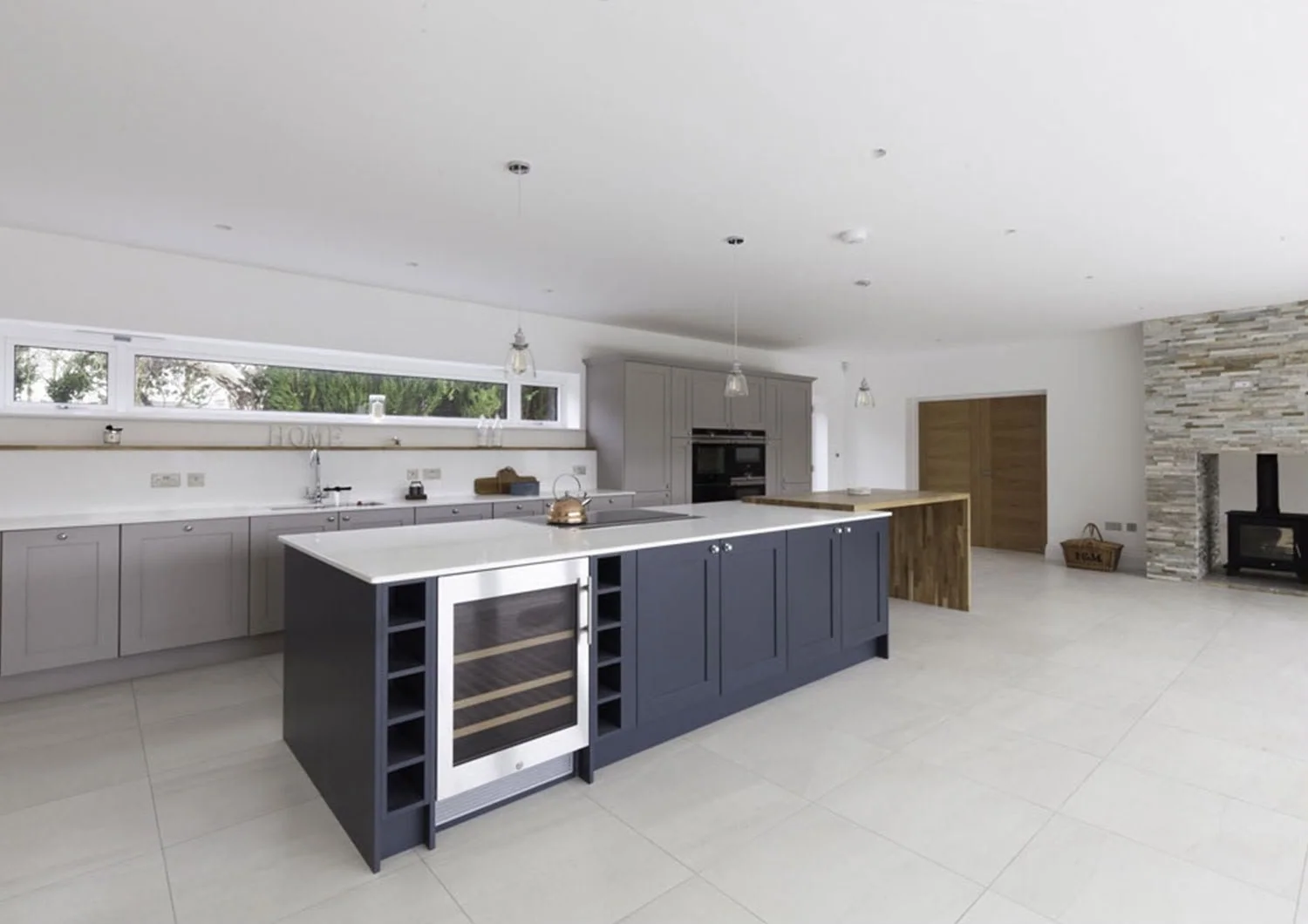 Open-plan kitchen with a navy island and a wine fridge