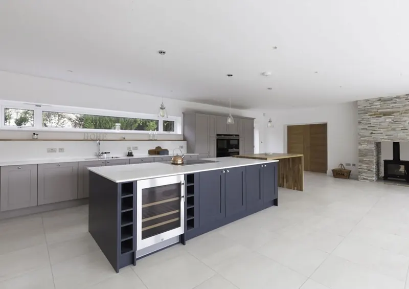 Open-plan kitchen with a navy island and a wine fridge, fitted by AB Woodwork