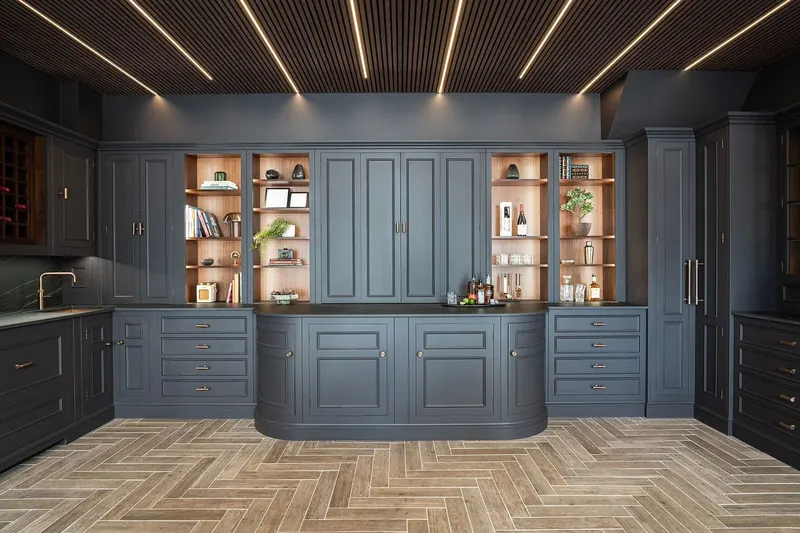 After: the same room with navy cabinetry, lit display shelves and a herringbone floor
