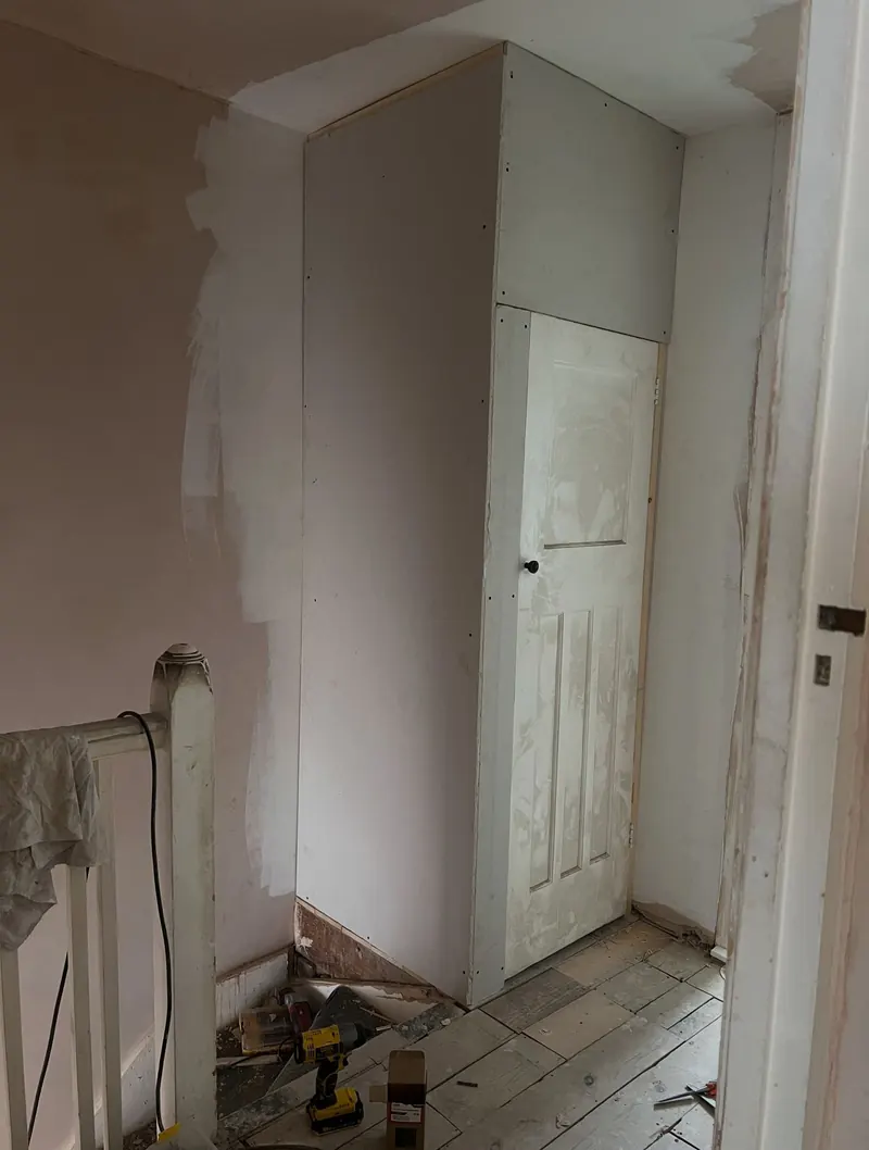 After: a boarded stud wall with a cupboard door